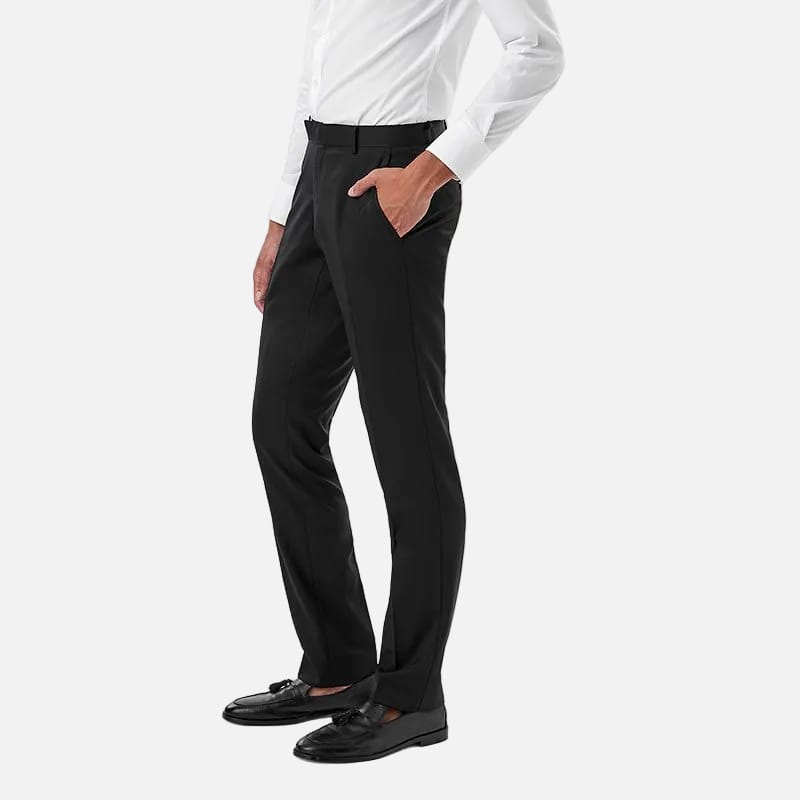 A man in a white long-sleeve dress shirt and black trousers, standing in profile against a solid white background.