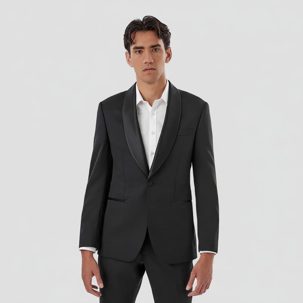 A man wearing a black tuxedo jacket with satin peak lapels, paired with a white dress shirt and matching black trousers, photographed against a solid white background.