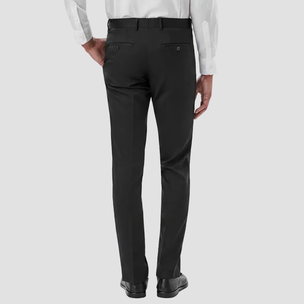 Rear view of a person wearing black dress pants with a white dress shirt and black dress shoes, shown against a plain white studio background.