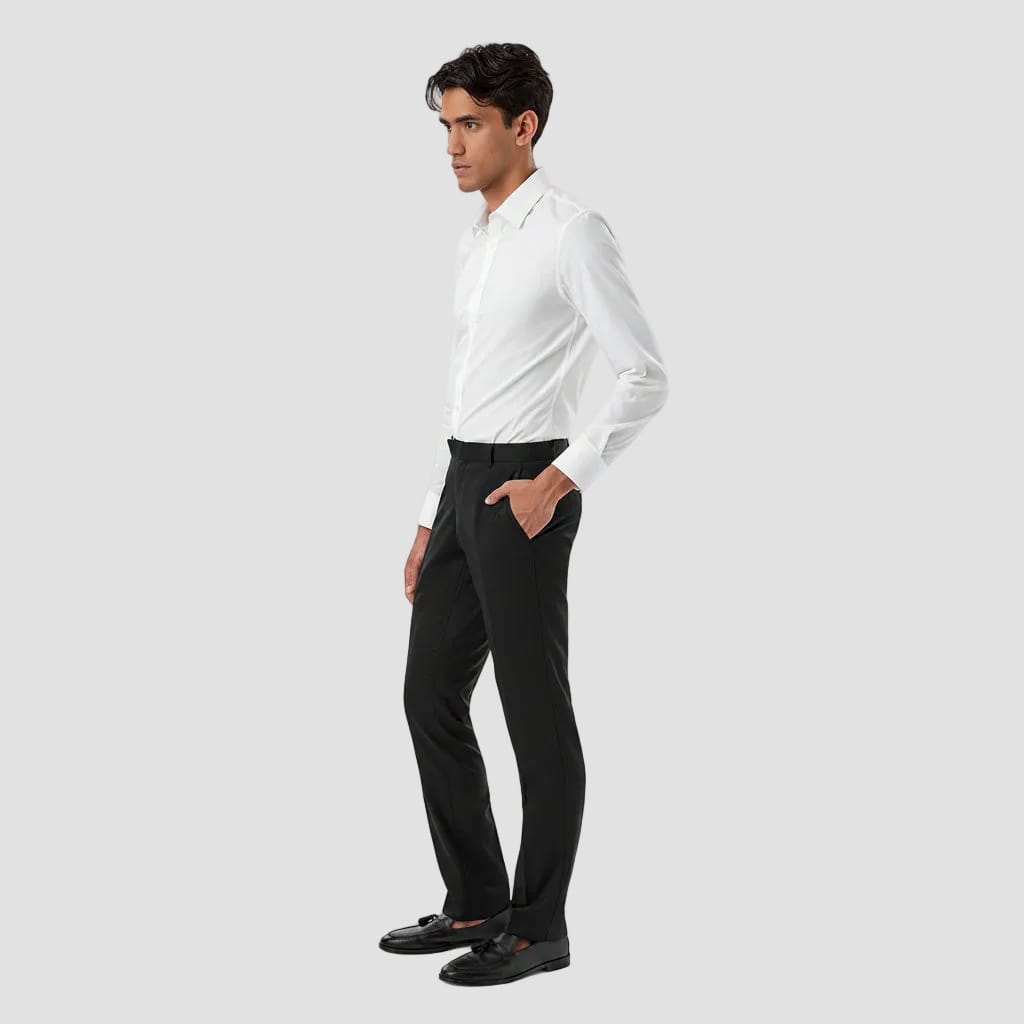 A man in a white long-sleeve dress shirt and black trousers, standing in profile against a solid white background.
