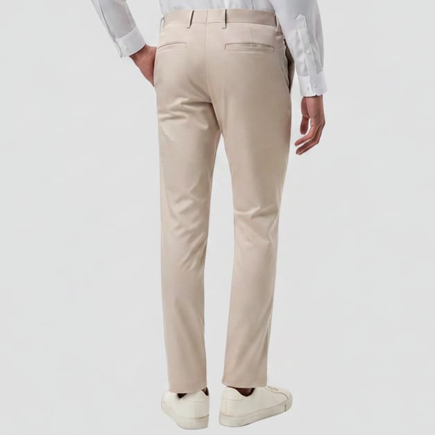 A person shown from the back wearing stone straight-leg chinos, a white long-sleeve shirt, and white sneakers against a plain white background.