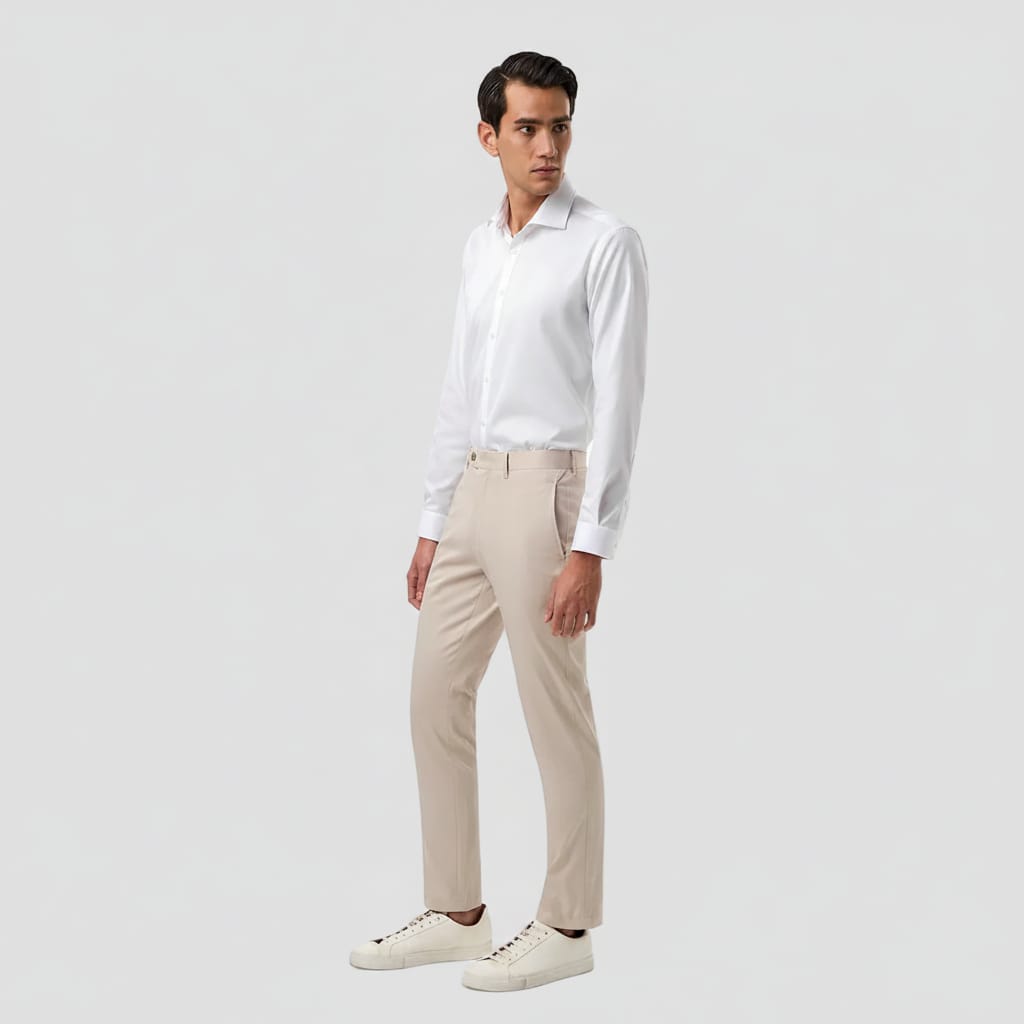 A man modeling a white long-sleeve button-down shirt, stone chinos, and white sneakers against a solid white background.