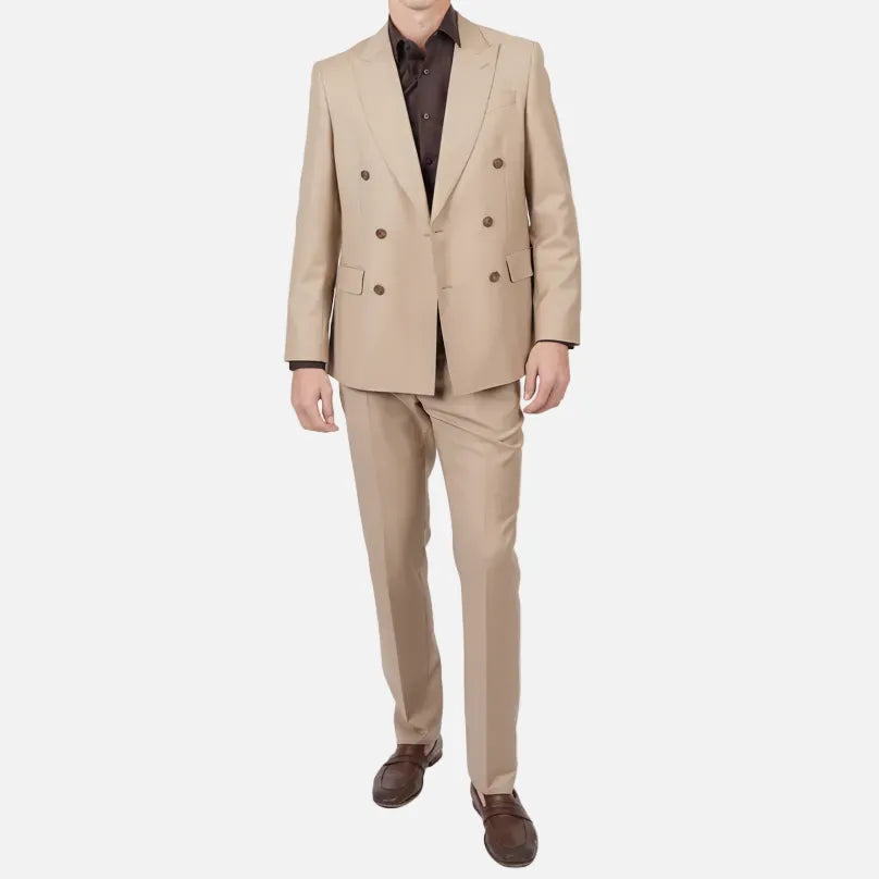 A man modeling a beige double-breasted suit with a dark brown shirt and brown leather shoes, standing against a plain white studio background.
