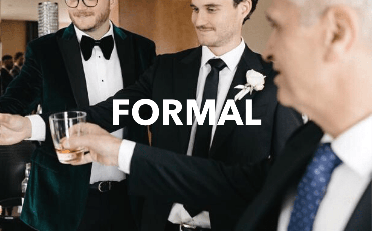 a bridal party cheers with their drinks at a wedding wearing mens formal suits