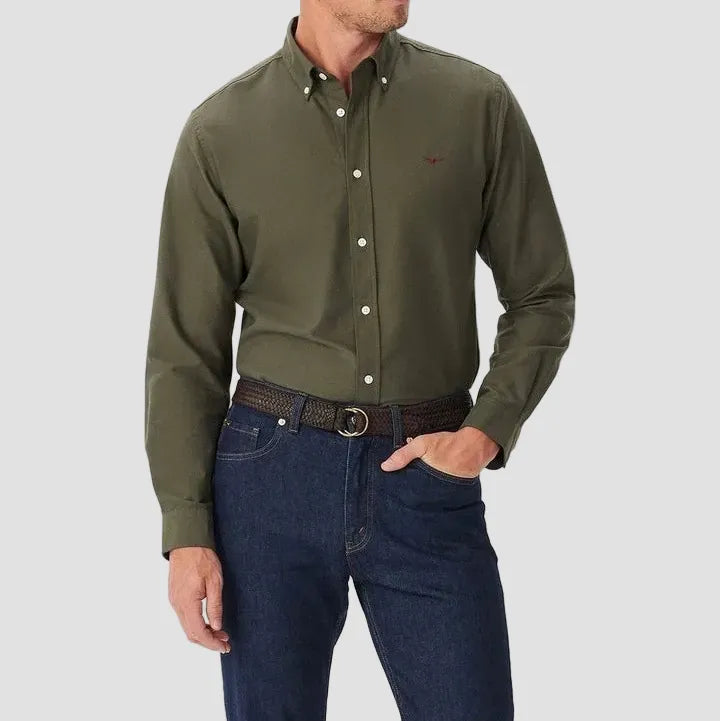 Man wearing a green button-up shirt and blue jeans on a white background