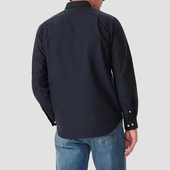 Man wearing a navy shirt and blue jeans on a white background