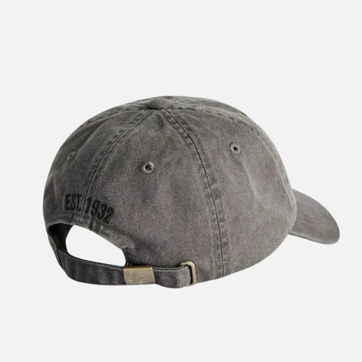 A washed dark gray baseball cap shown from a three-quarters back angle, featuring 'EST. 1937' embroidered on the side and an adjustable strap with a brass-colored metal buckle.
