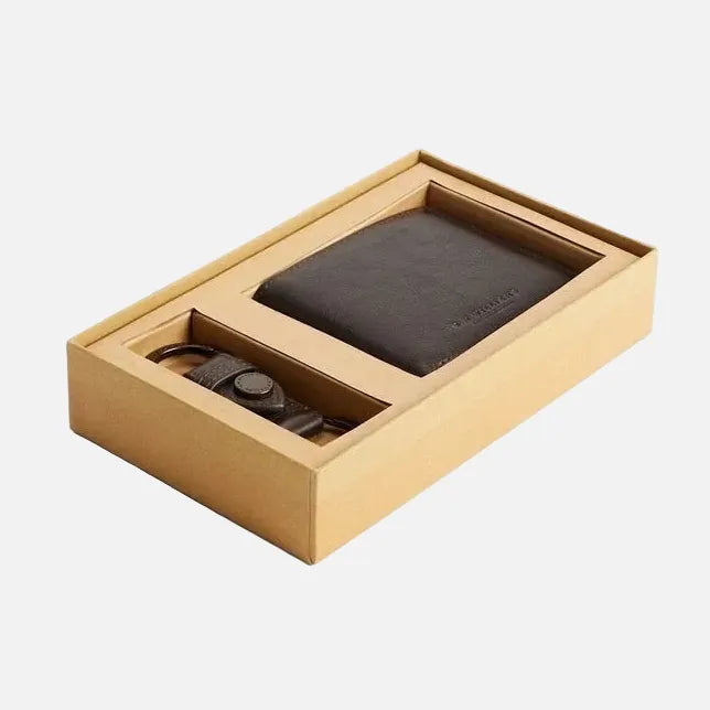 A men's gift set in a light brown cardboard box, featuring a dark brown leather bifold wallet and a matching leather strap watch.