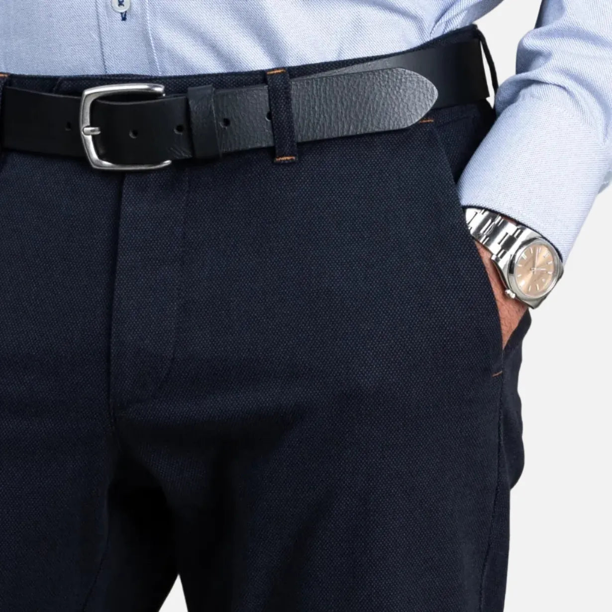 Person wearing navy pants with a black belt and light blue shirt on a gray background