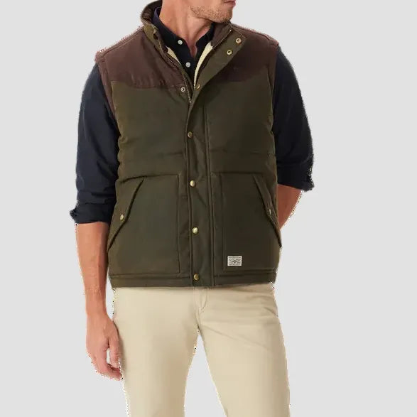 Man wearing a green vest over a dark shirt on a white background