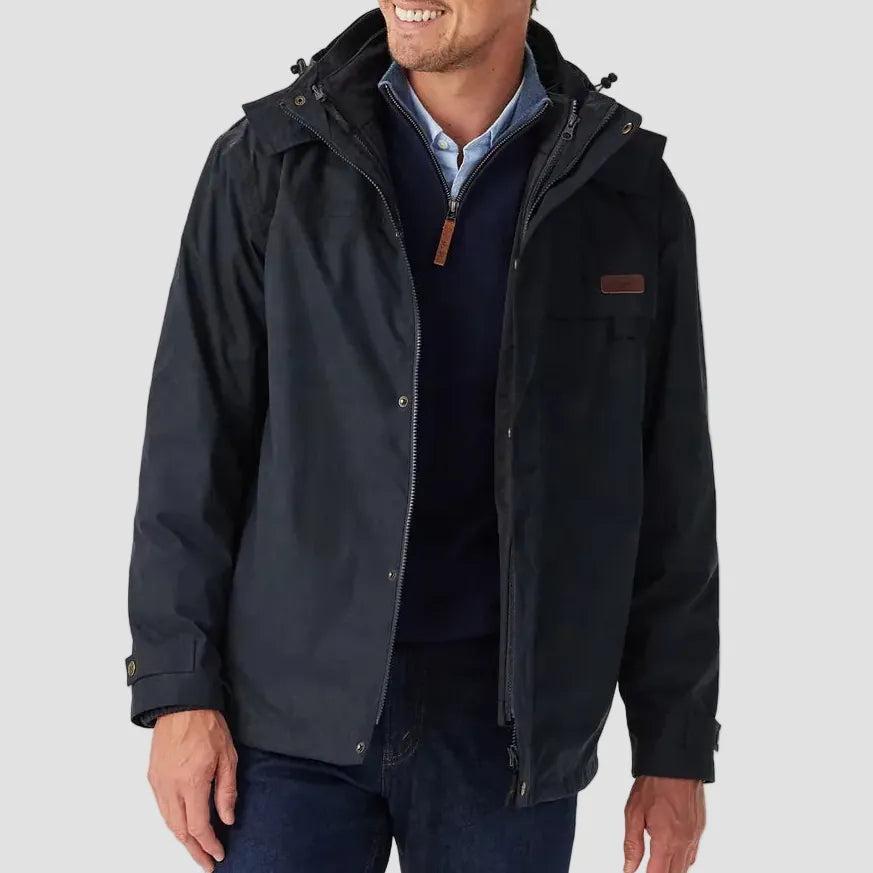 Man wearing a black jacket with a hood on a light gray background