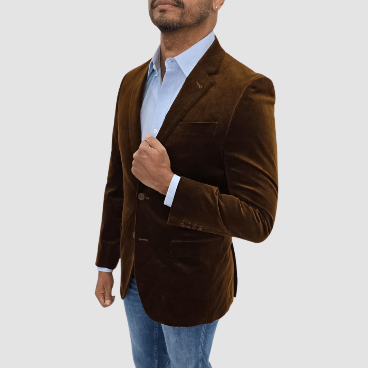 A man wearing a camel-colored, tailored-fit, cotton corduroy sports jacket by Savile Row, with a notch lapel, two-button closure, and flap pockets, over a light blue shirt. Limited stock.