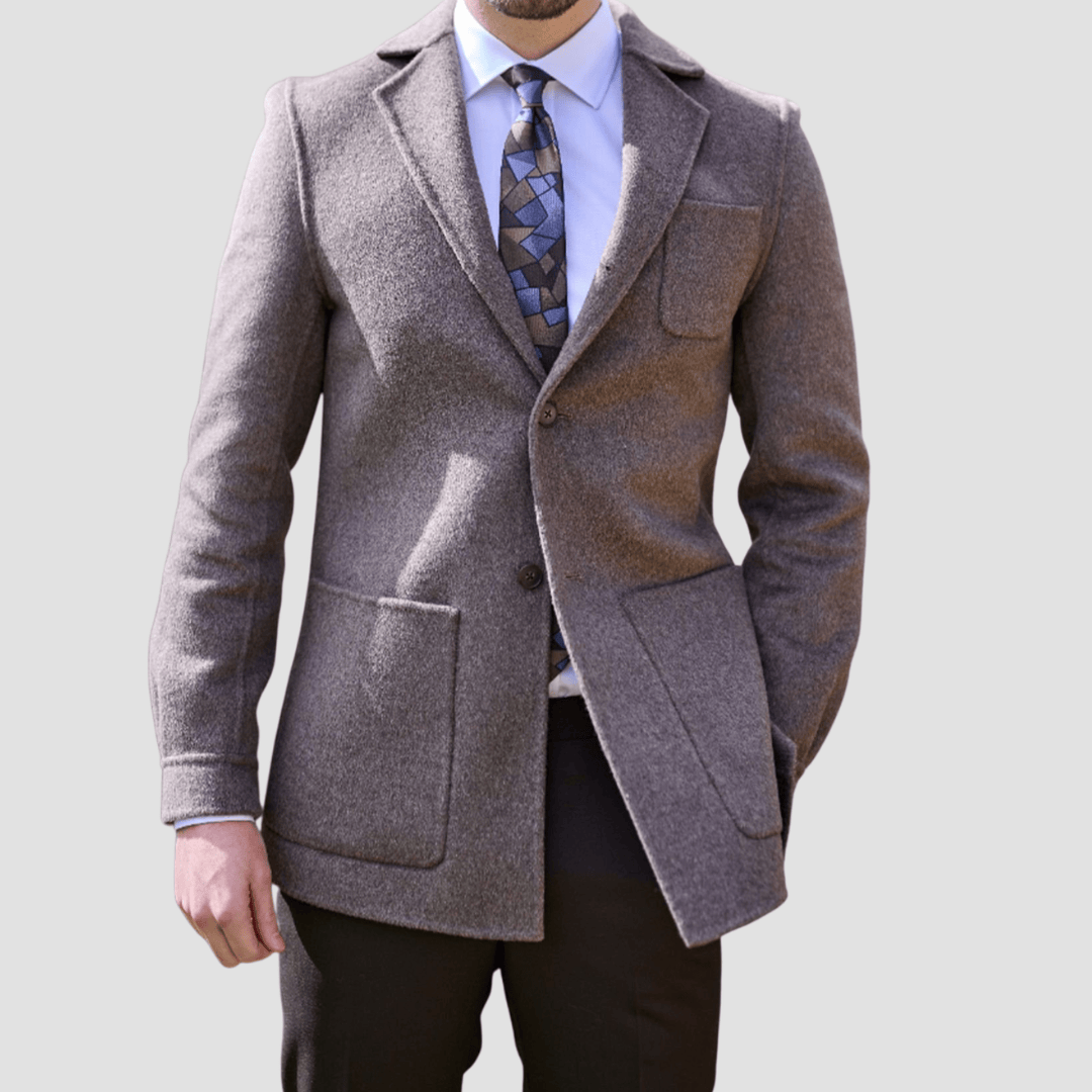 Man wearing a brown coat with a patterned tie and shirt