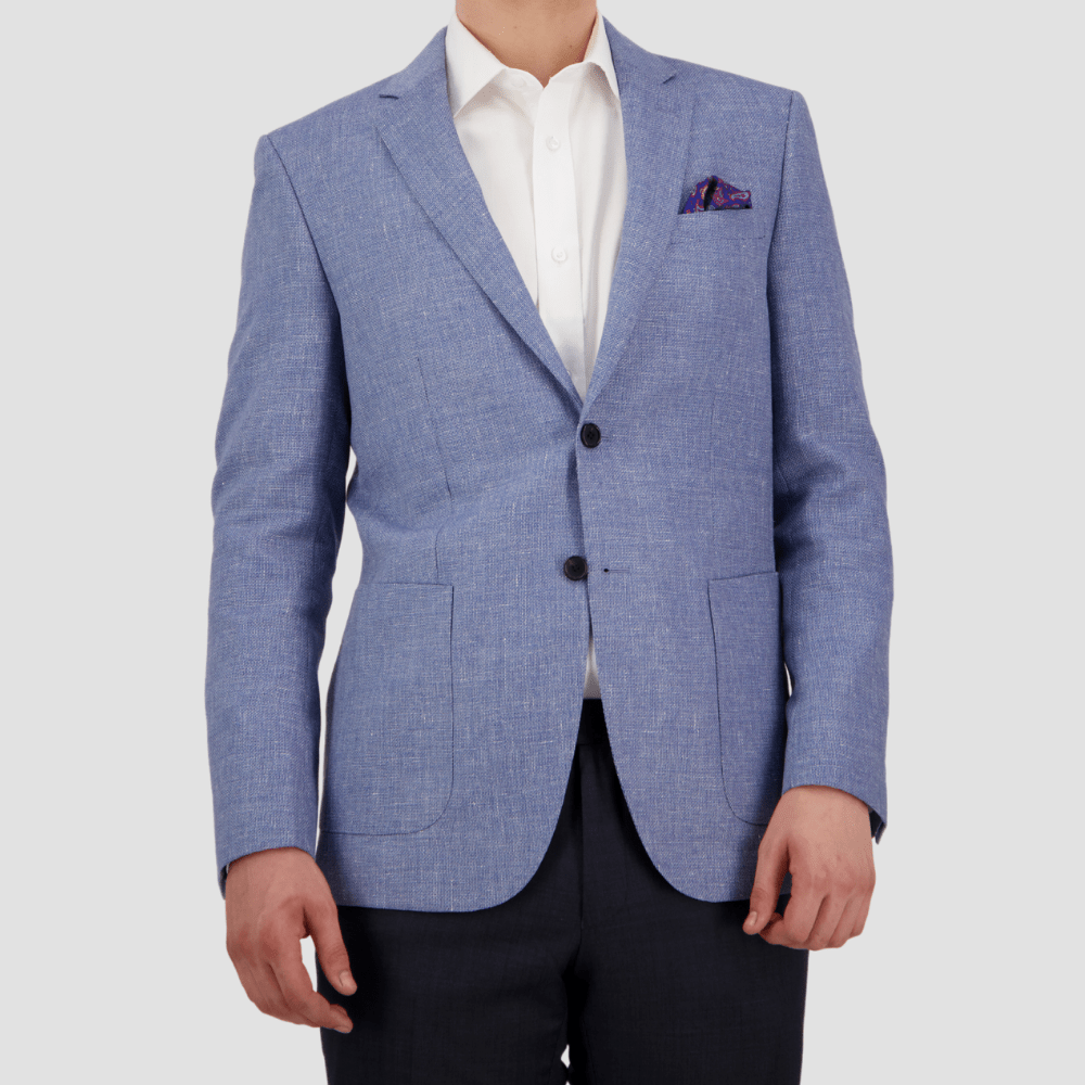 A man wearing a sky blue sports jacket by Savile Row with notch lapel, double button closure, and welt chest pocket, paired with a white shirt and dark trousers.