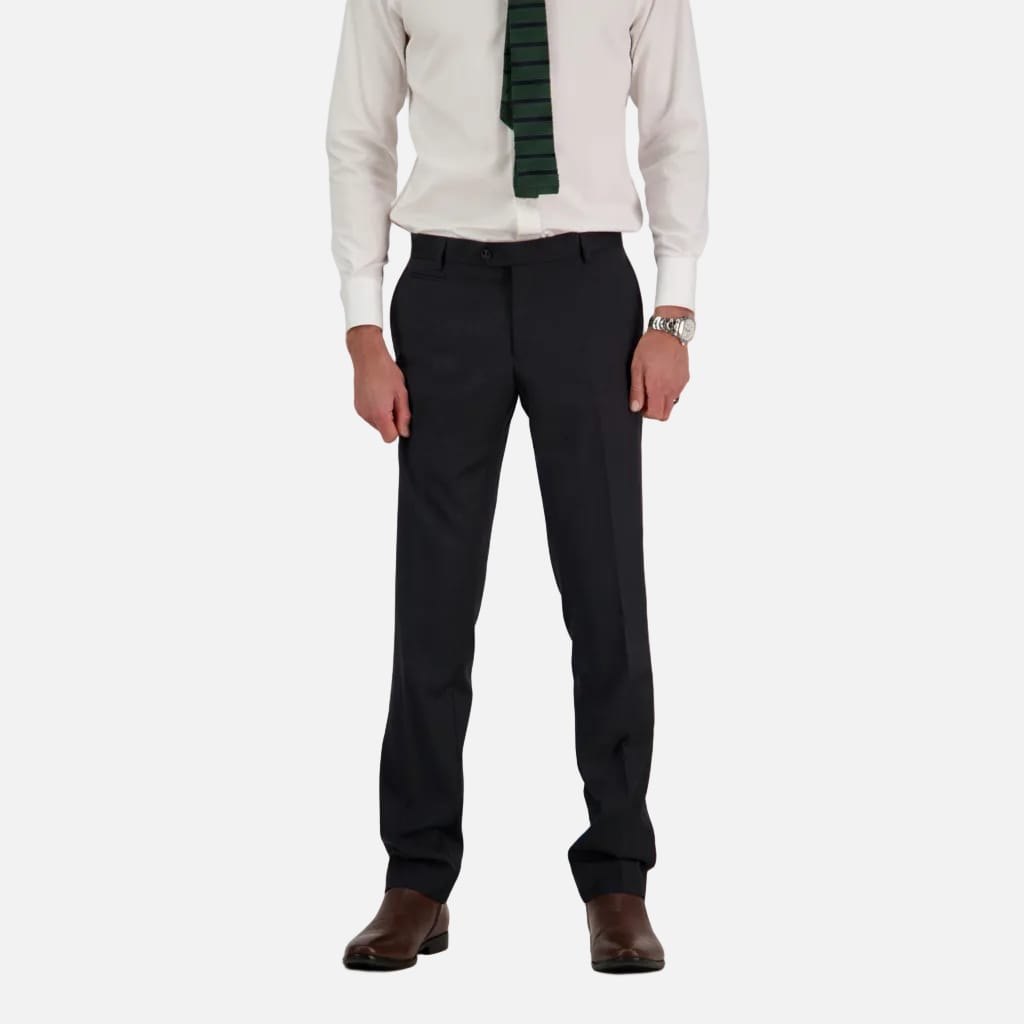 Person wearing black dress pants with a white shirt and brown shoes on a plain background