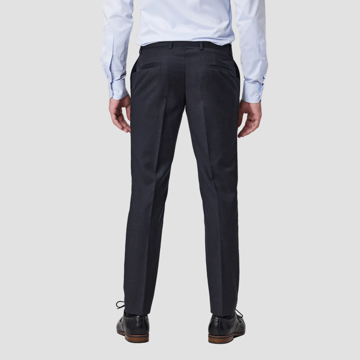 Person wearing slim fit charcoal wool blend pants by Savile Row with a light blue shirt and black dress shoes