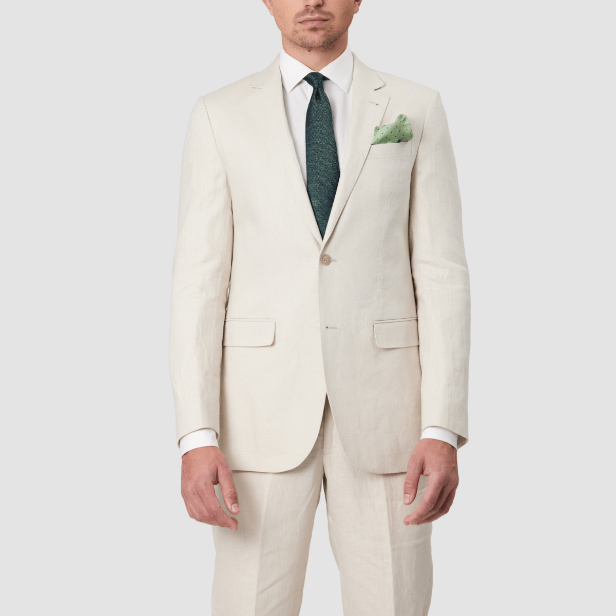 Mens single breasted, pure linen suit in ecru by Savile Row with a green tie and pocket square.