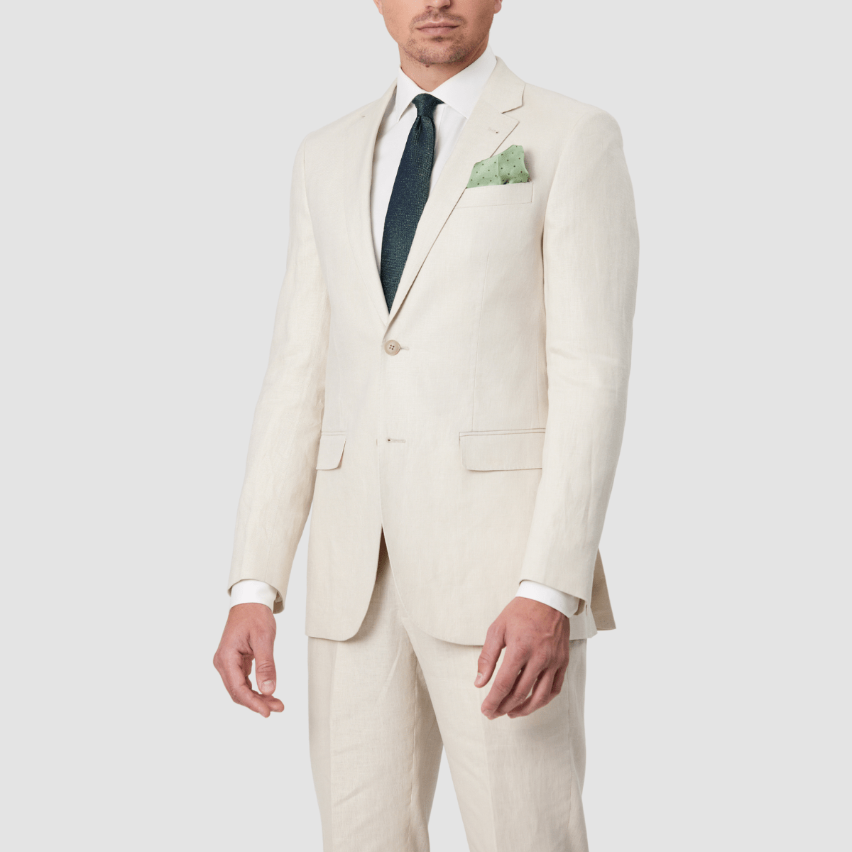 Mens single breasted, pure linen suit in ecru by Savile Row with a green tie and pocket square.