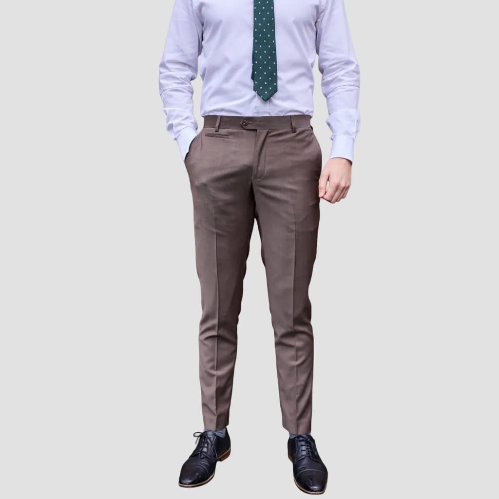 A person wearing slim-fit brown dress pants, a white dress shirt, a green polka-dot tie, and black leather dress shoes, shown from the waist down against a light gray studio background.
