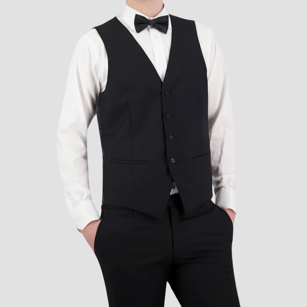 A man wearing a classic fit black vest with a four button front, paired with a white shirt and a bow tie.