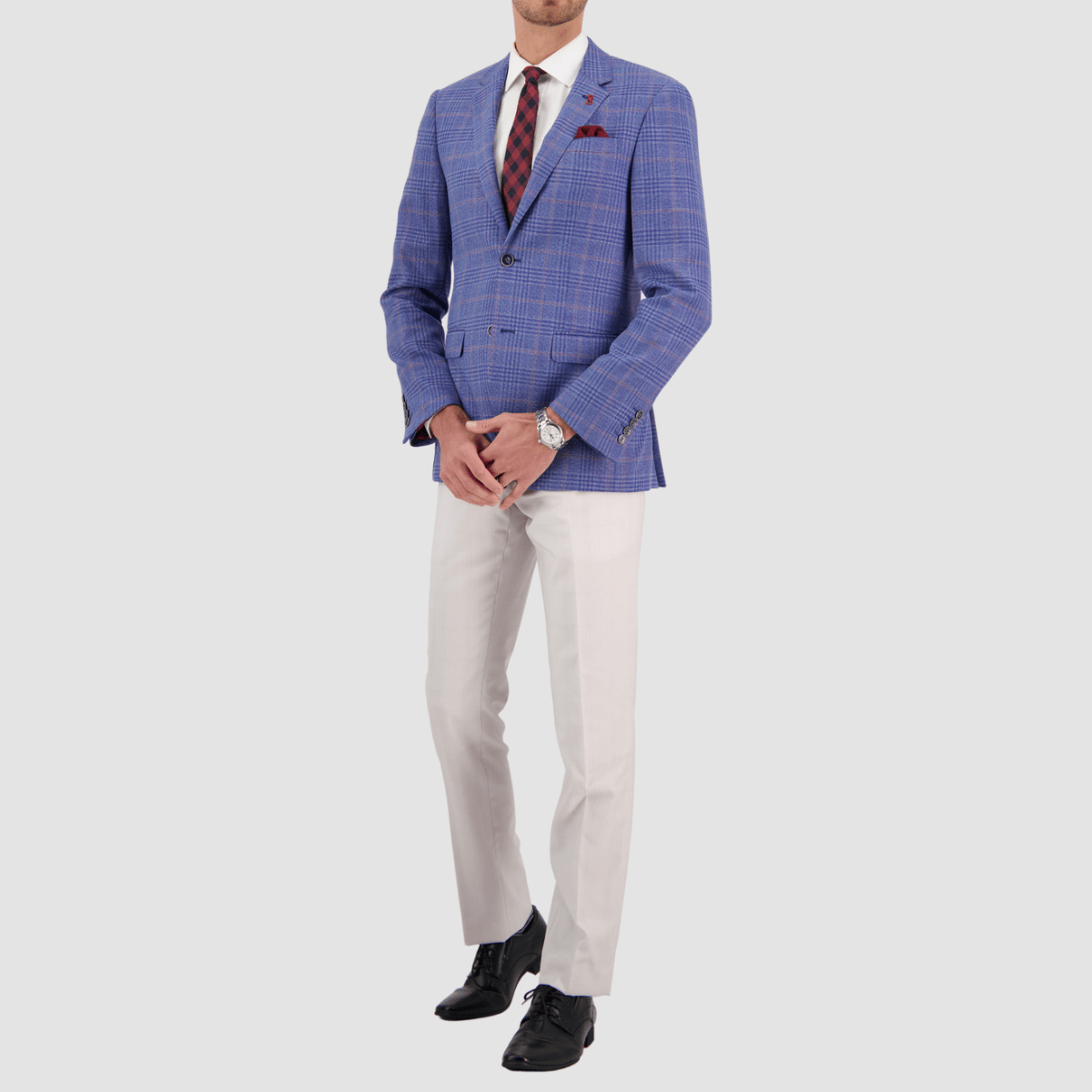 A man wearing a sky blue wool checked sports jacket with a slim fit, notch lapel, double button, and a chest pocket. The jacket is paired with white trousers, a white shirt, and black shoes.