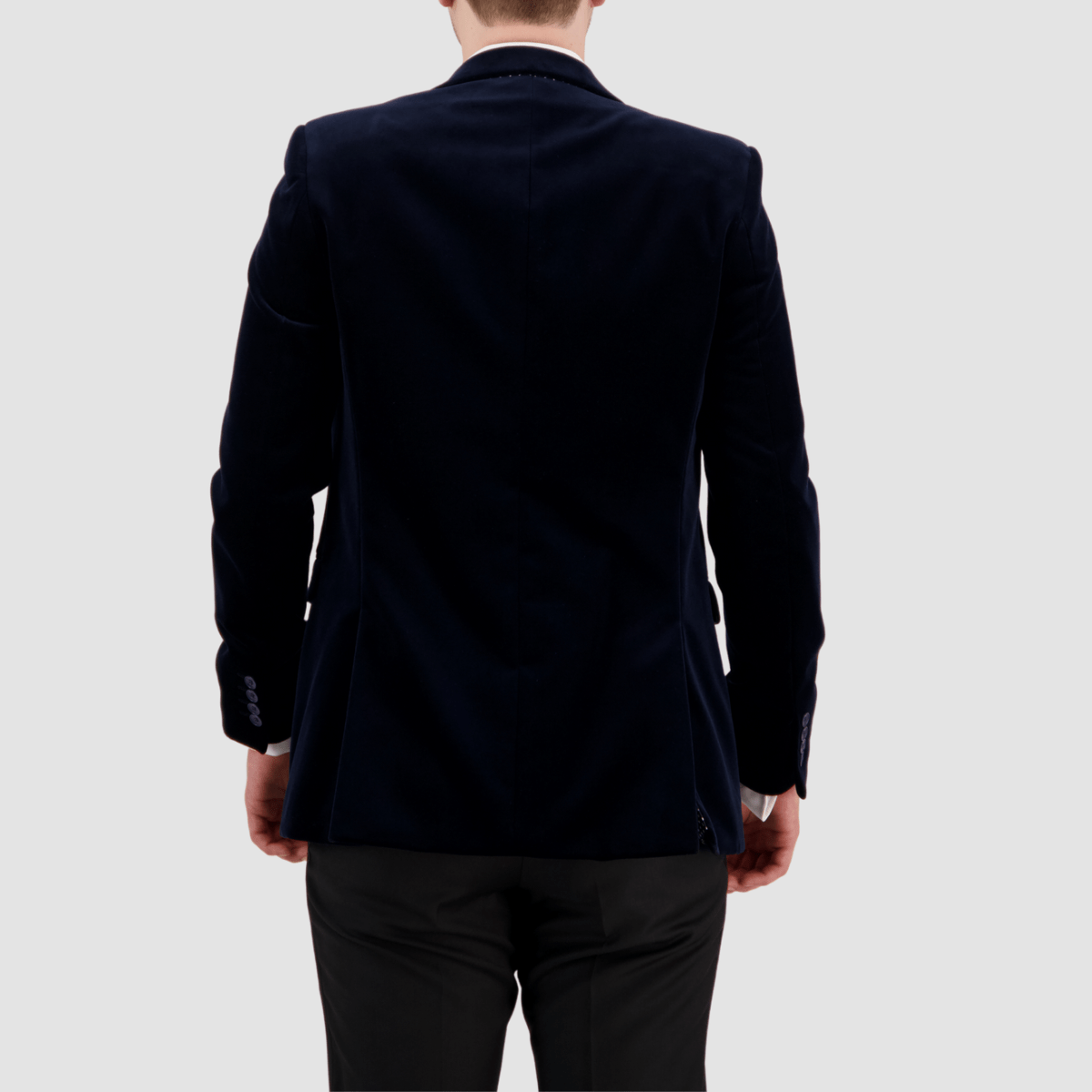 A man wearing a navy velvet sports jacket with a slim fit and peak lapel by Savile Row.