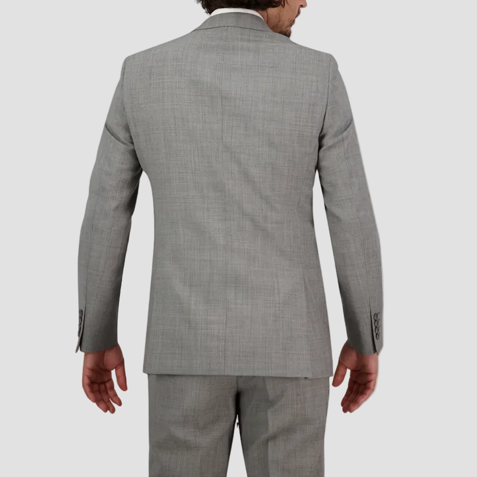 A man standing, wearing a chrome grey tailored fit suit, double vented, with a white shirt and trousers.