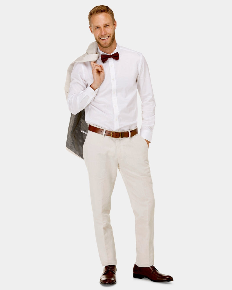 man wears a beige linen suit with a white shirt and red bow tie