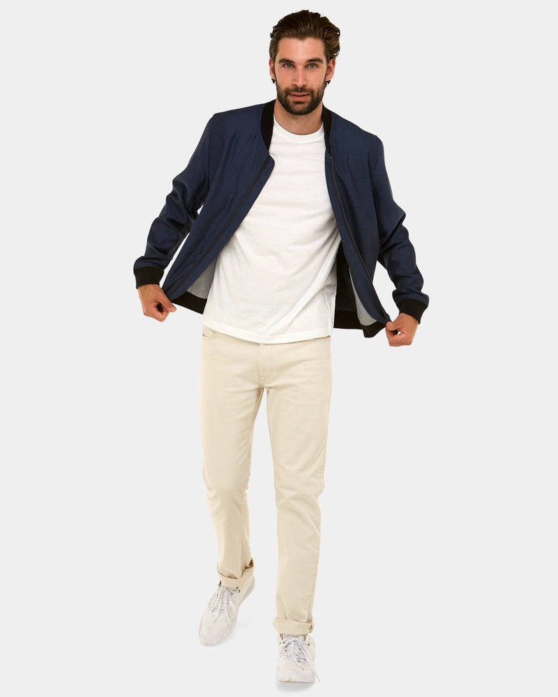a mens navy bomber jacket over a white tee and beige chinos