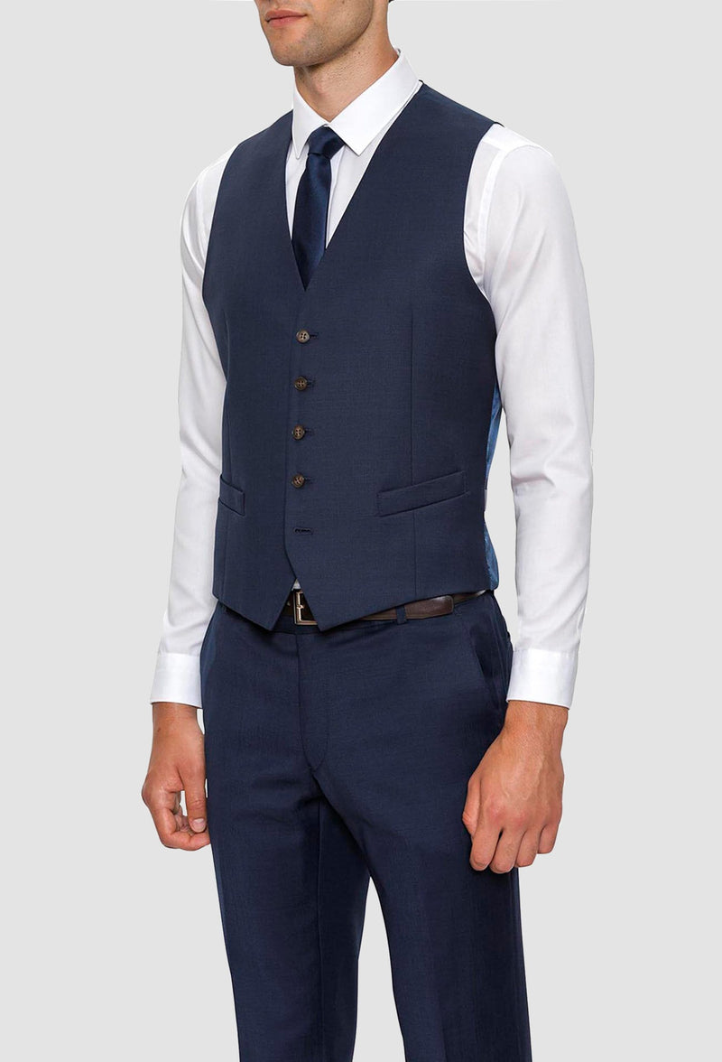 A model wears the Gibson slim fit mighty vest in navy pure wool with a white shirt and navy tie