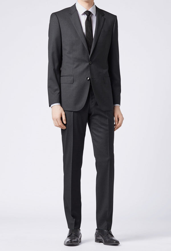 A full length frontal view of a man standing in the Hugo Boss classic fit johnstons suit in dark grey 