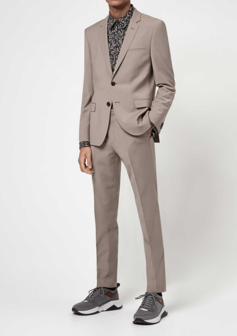  a model wears the Hugo slim fit arti hesten suit in medium beige pure wool with grey sneakers and a black printed shirt