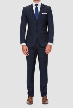 A full length view of the Joe Black slim fit anchor suit in navy pure wool FJV033 styled with a white shirt and a blue tie on a grey background