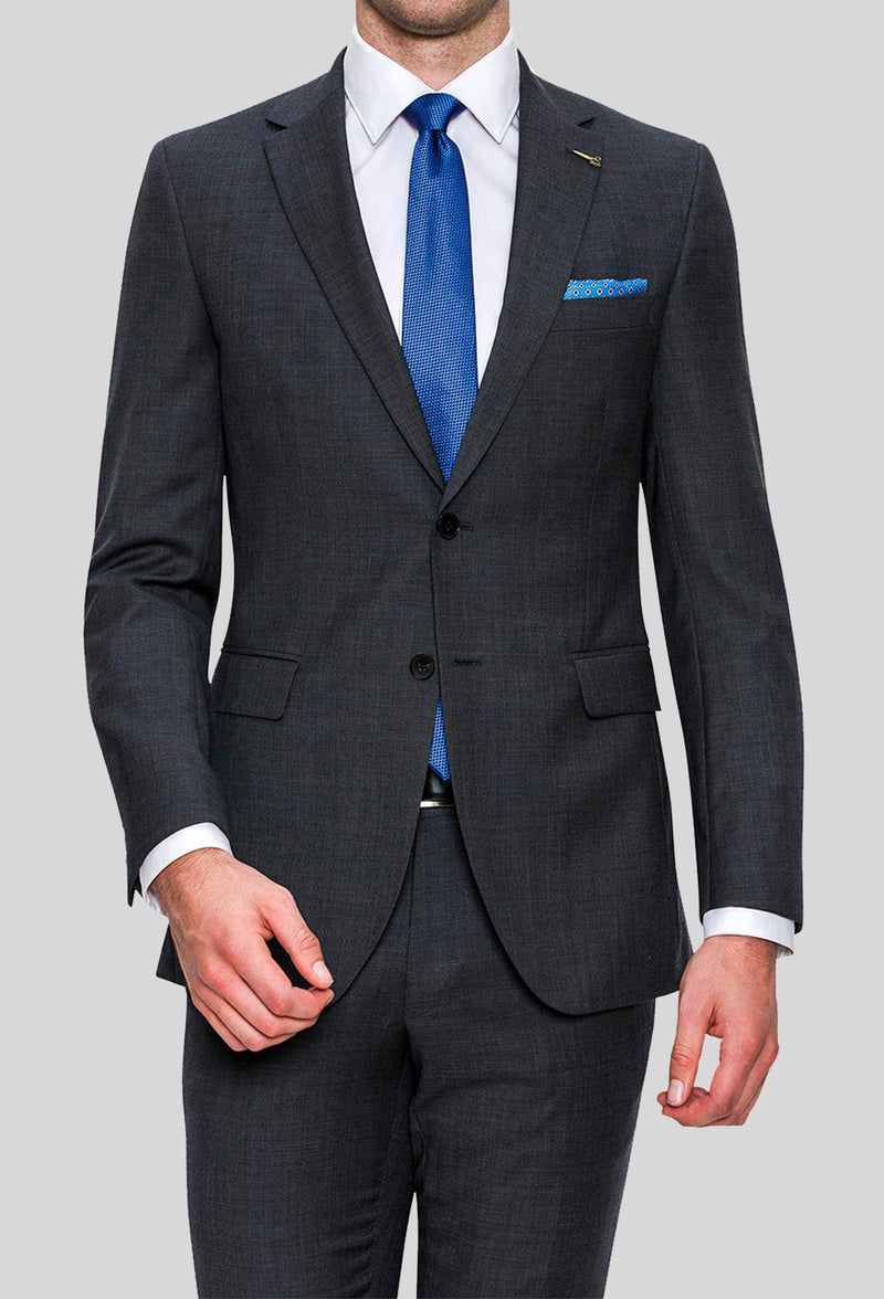 A model wears the Joe Black slim fit sergeant suit in charcoal pure wool FJD899 with a white shirt and a blue tie