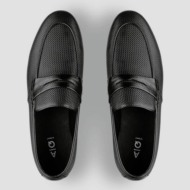 a top view showing the apron detail across the front of the black leather penny loafers from aquila