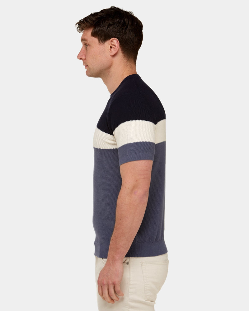 a side view showing the slim fit of the mens knitted tshirt in navy and blue block stripe