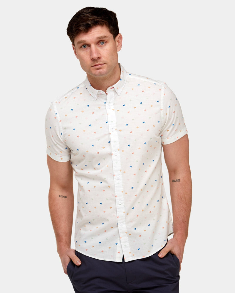 a white short sleeve shirt with small palm print all over in blue and orange