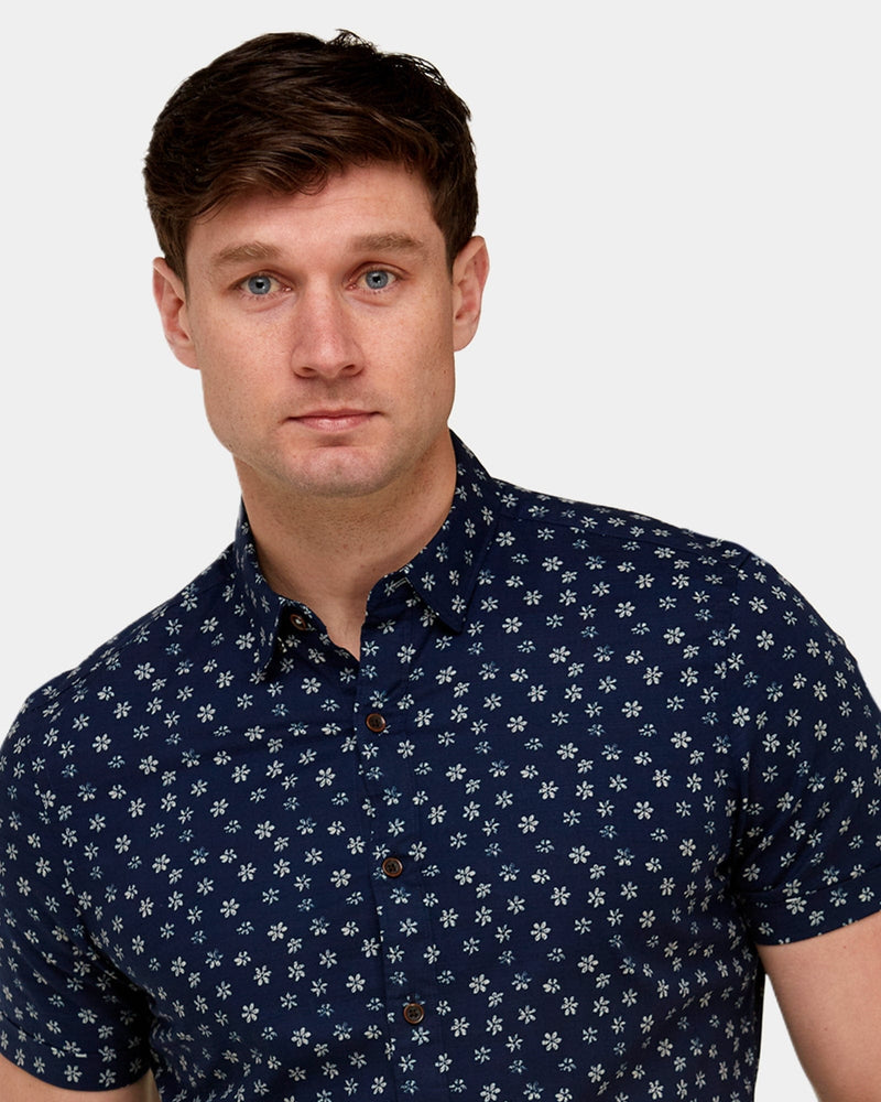 a small white floral print over a cotton navy shirt and dark brown buttons down the front