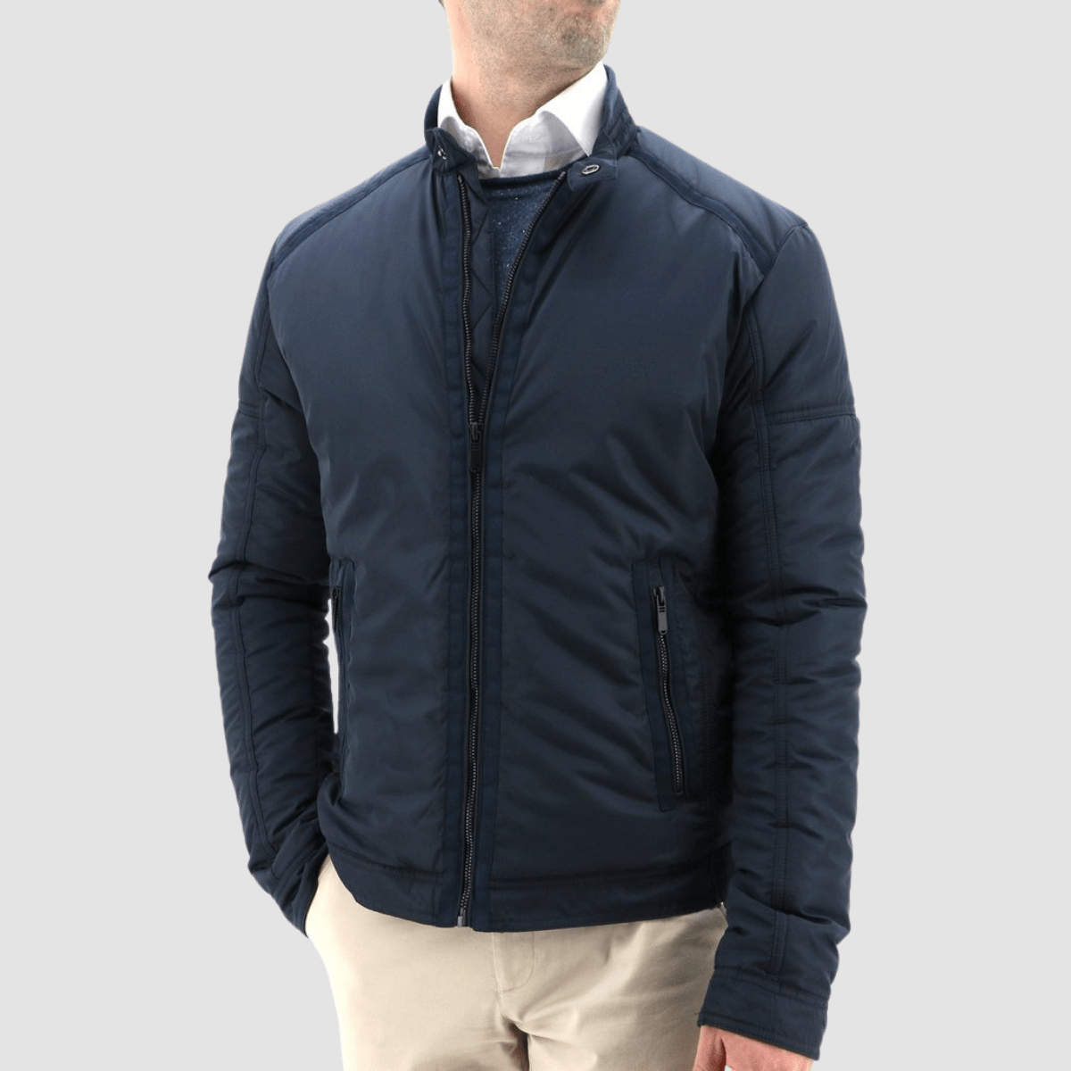 a model wears a blue bomber jacket over a lighter blue knit and white shirt