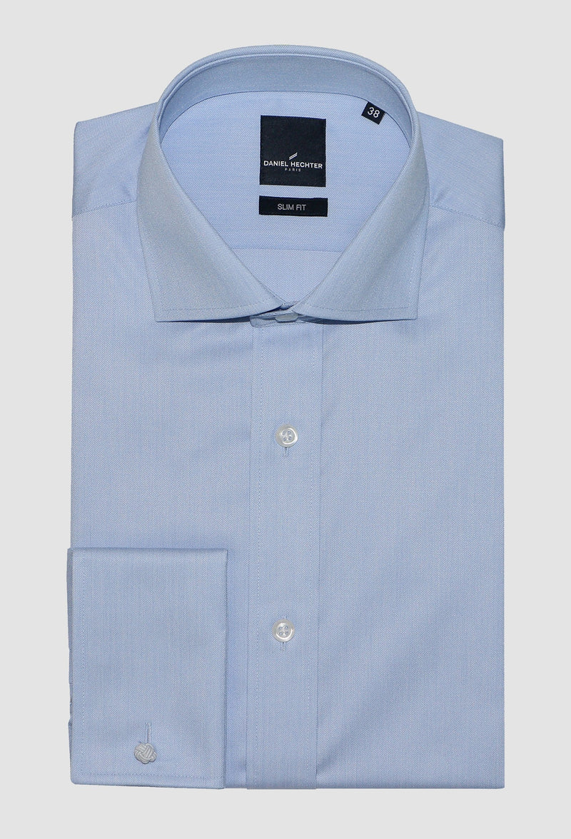 blue cotton business shirt by daniel hechter folded on a grey background showing the front button and french cuff detail