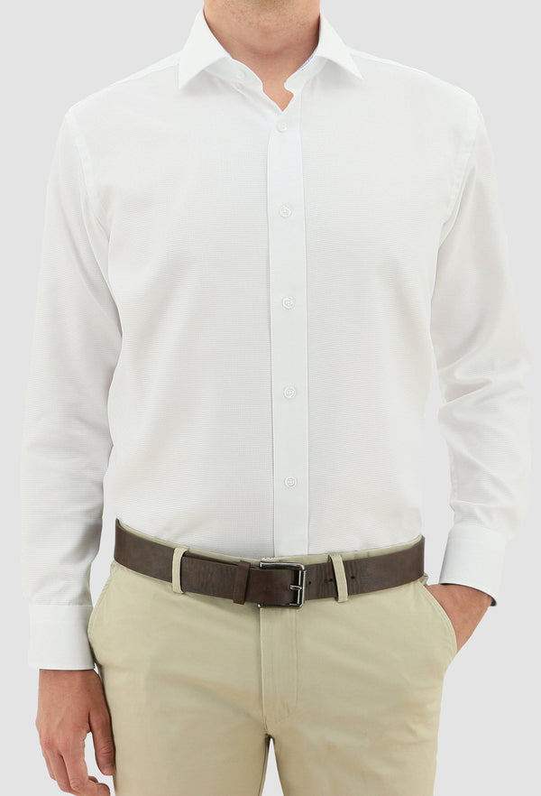 a model faces the front wearing the daniel hechter slim fit jacques mens business shirt in white pure cotton styled with a chocolate brown belt and sand coloured trousers