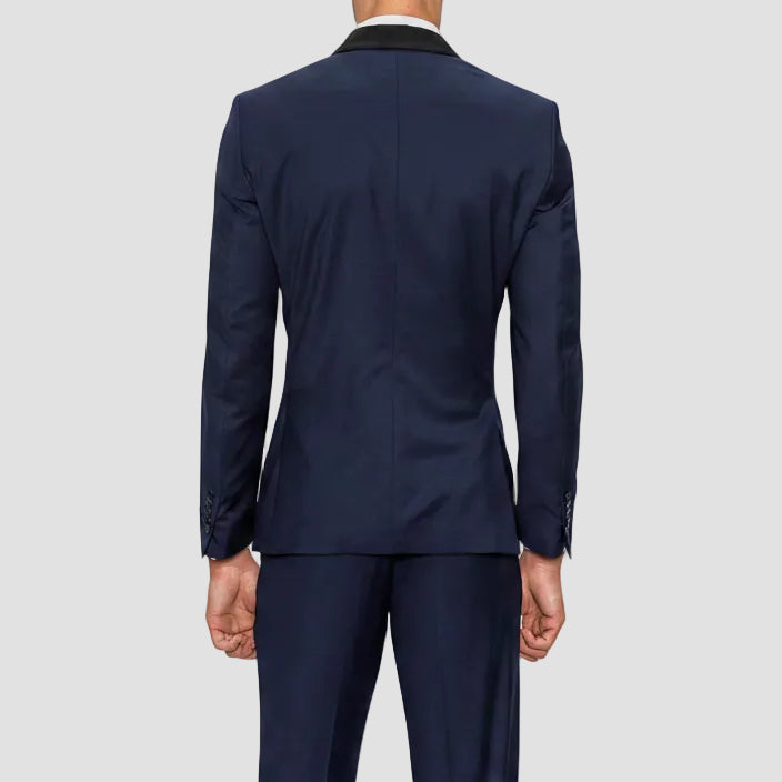 Gibson’s Spectre navy tuxedo blends a satin shawl lapel, jet pockets and 2‑button front with slim trousers.