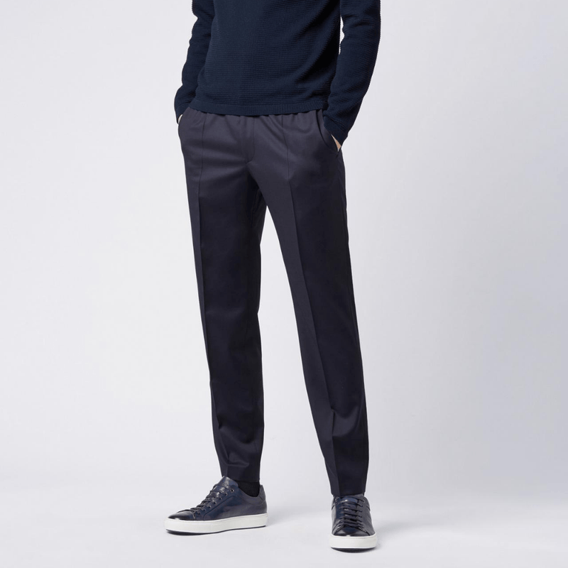 a model wears the hugo boss navy leather trainers with a suit pant and navy knit