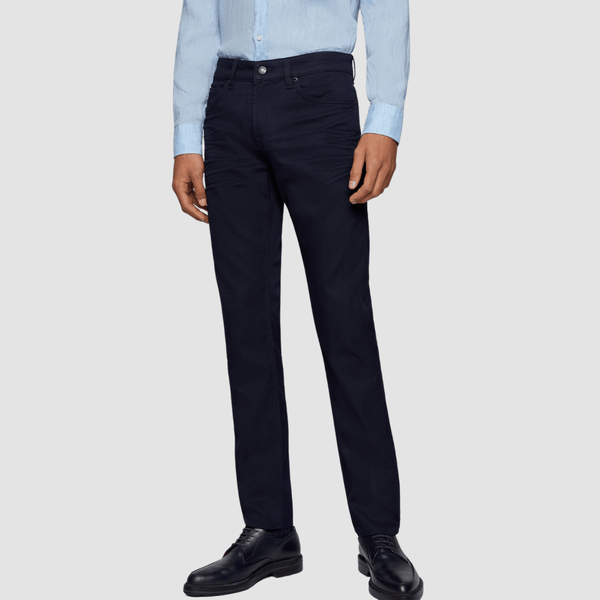 a front view of a man wearing dark slim fit hugo boss jeans with black leather shows and a light blue shirt tucked in