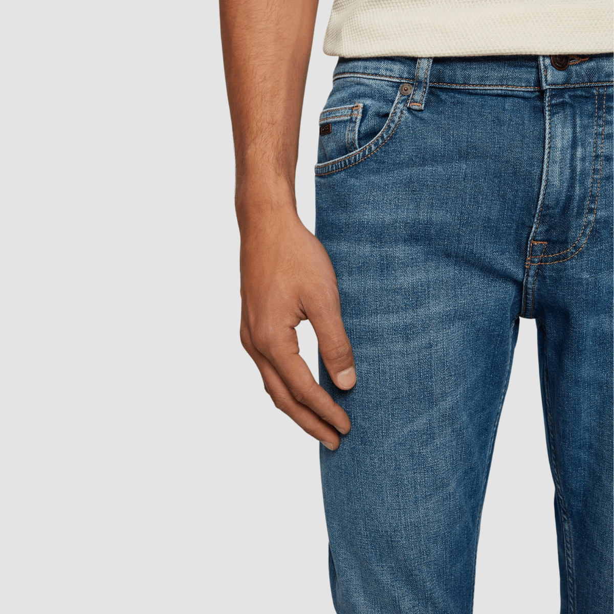 close up fo the side and coin pockets on the mid blue wash denim jeans, brass button and zip fastener at the front