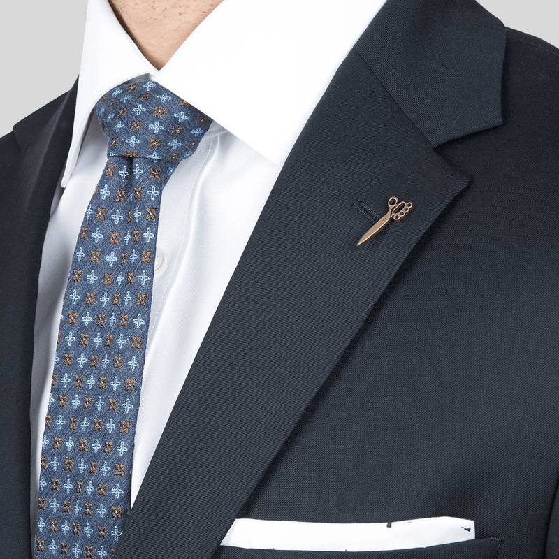 a close up of the joe black mens suit with a notched lapel and bronze lapel pin