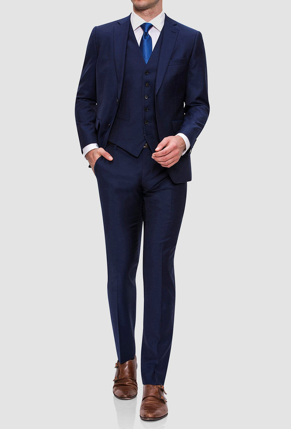 A model walking and wearing the Joe Black slim fit anchor suit in navy pure wool FJY100 styled with a white shirt and a blue tie