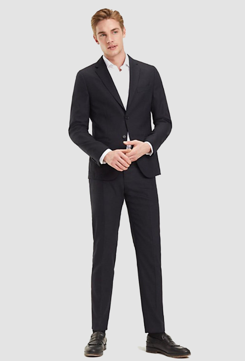 a model wears the Tommy Hilfiger slim fit virgin wool suit in black with a white shirt 