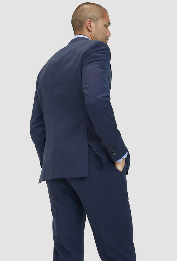 A model faces the back showing up the back details on the Tommy Hilfiger slim fit virgin wool blazer in navy blue